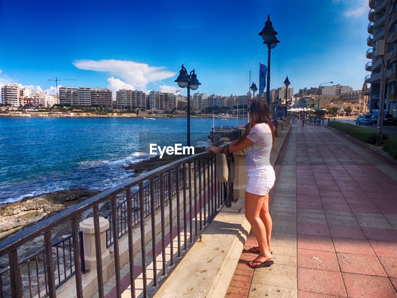 REAR VIEW OF WOMAN WALKING ON BRIDGE