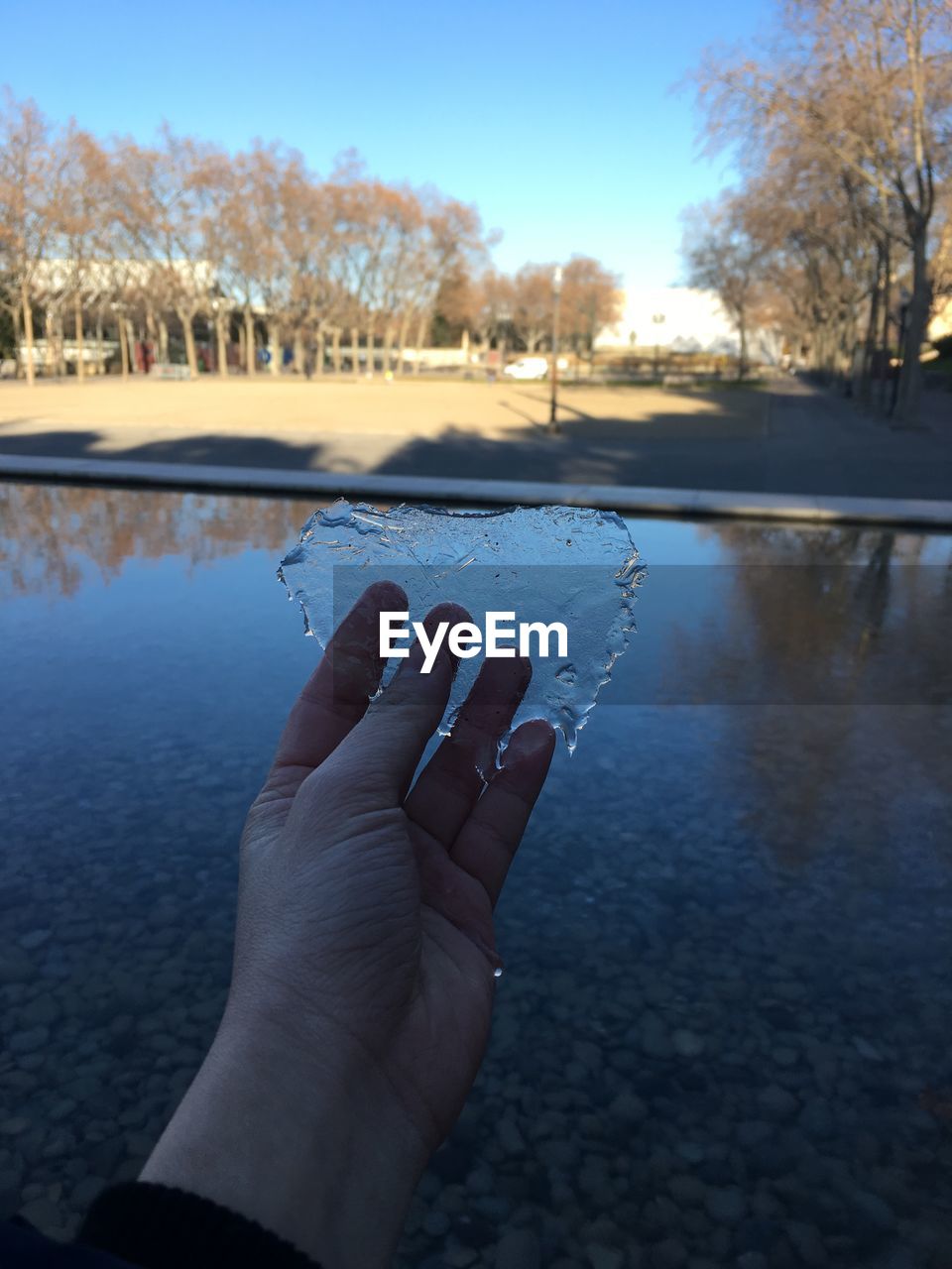 Cropped hand of woman holding snow against sky