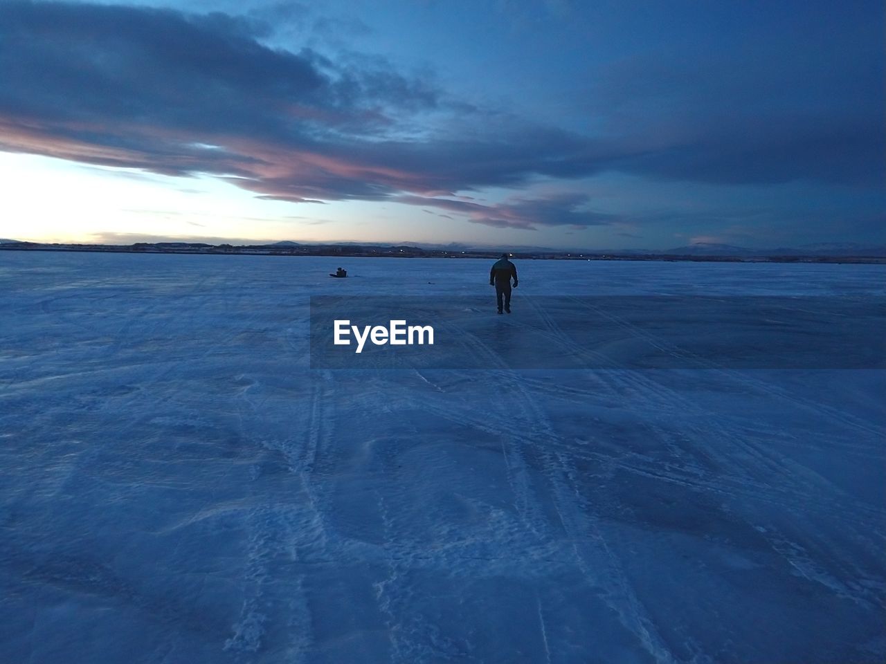 PERSON WALKING ON SNOW COVERED LAND AGAINST SKY