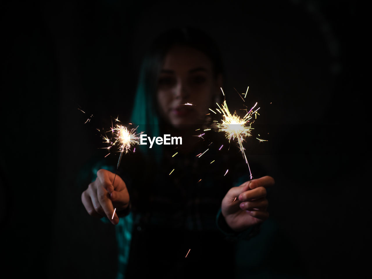 Young woman holding sparklers at night