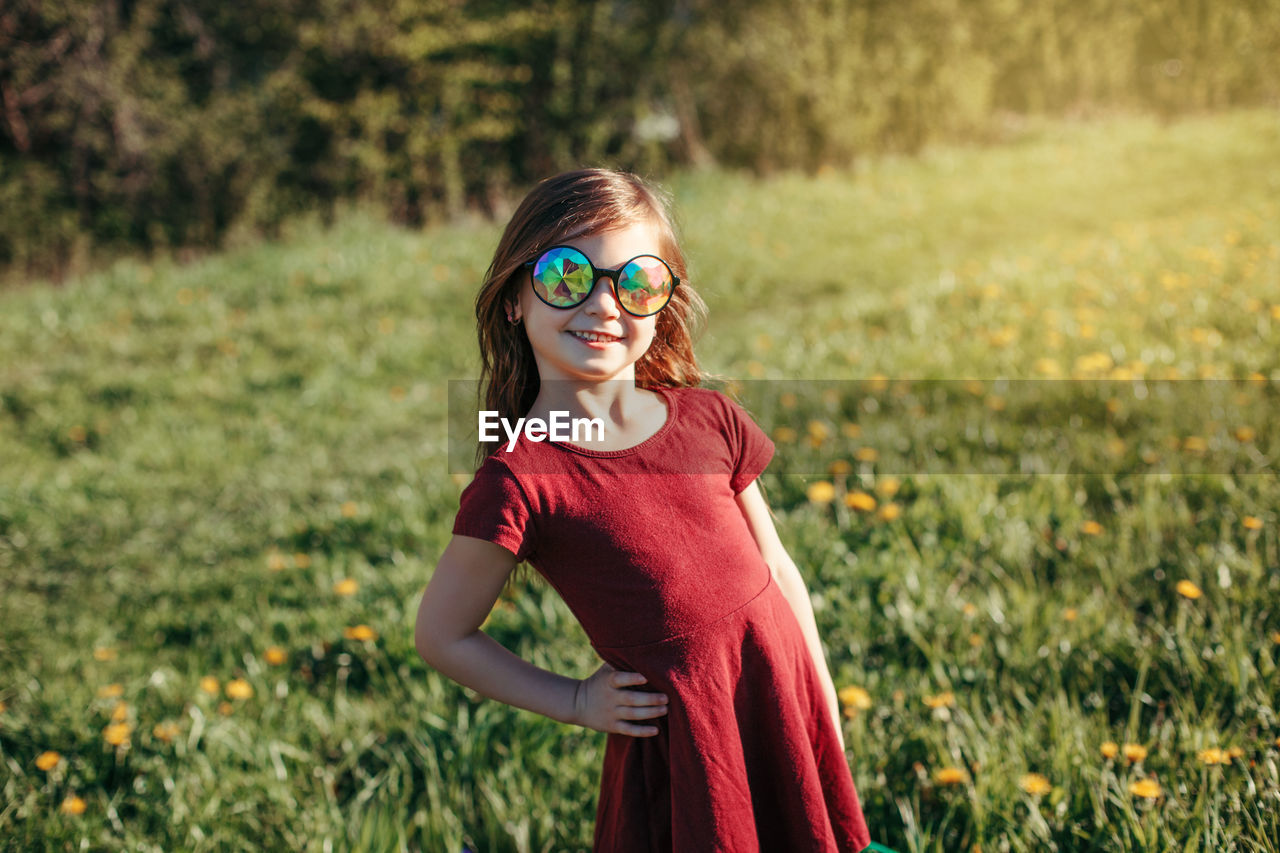 Portrait of smiling girl wearing sunglasses standing on field