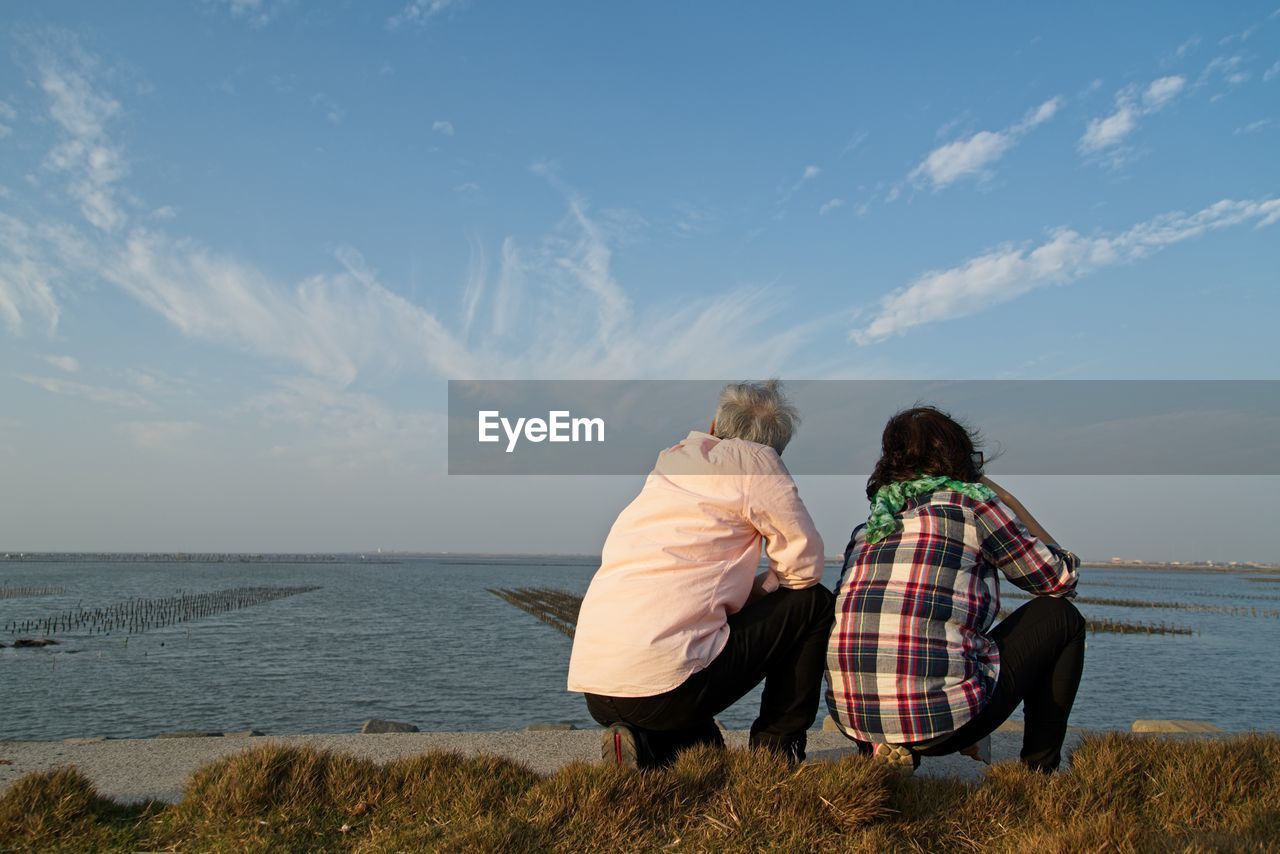 Rear view of couple sitting against sky