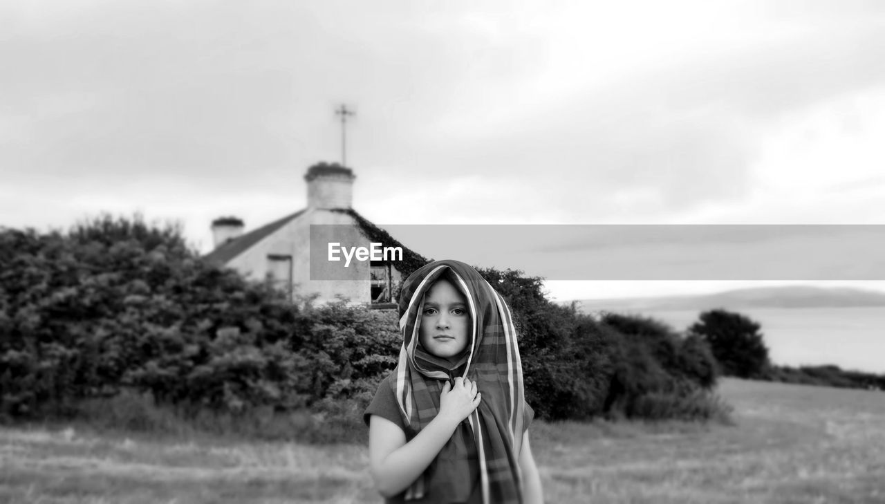 Portrait of girl covered head with shawl while standing on field