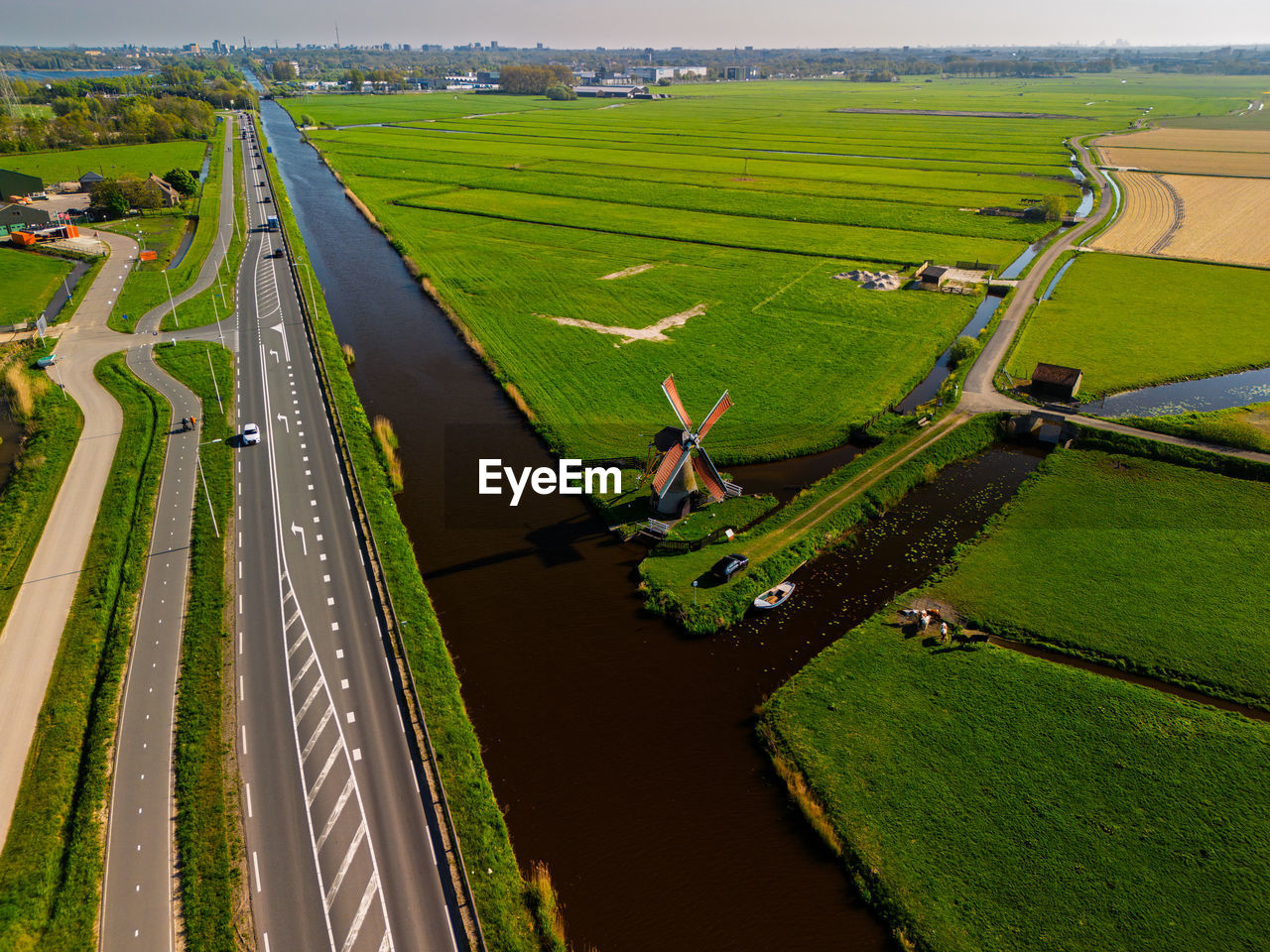 Aerial view of a dutch countryside with a traditional windmill by canal green fields and nearby road