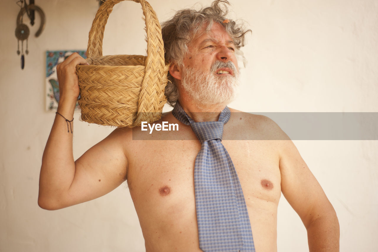 PORTRAIT OF SHIRTLESS MAN HOLDING WALL