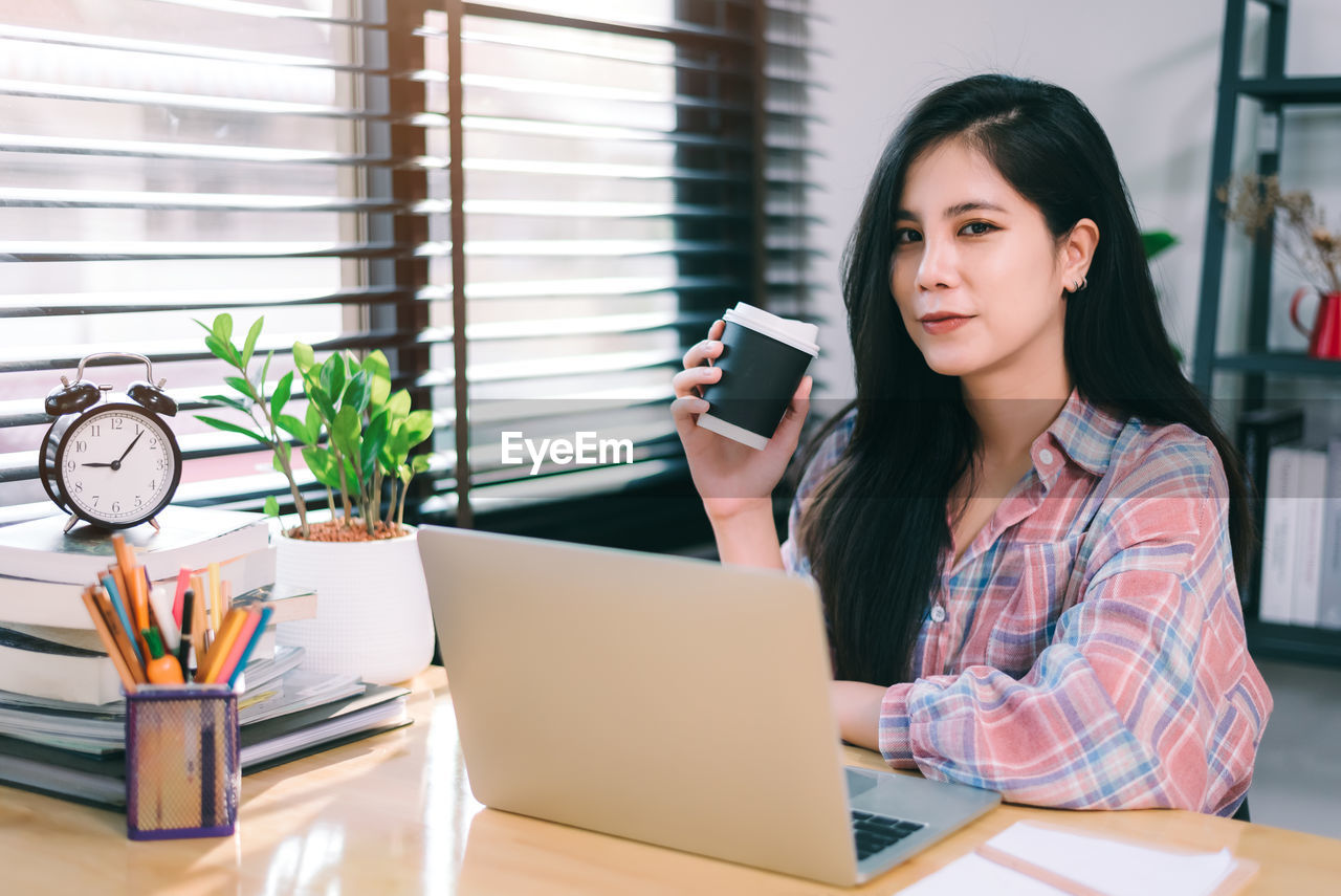 young woman using phone while sitting at table