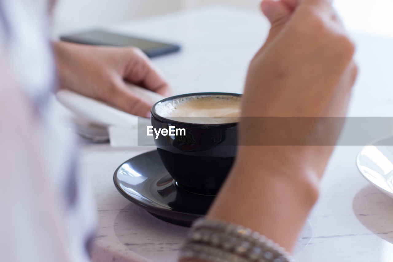 Midsection of man holding coffee cup