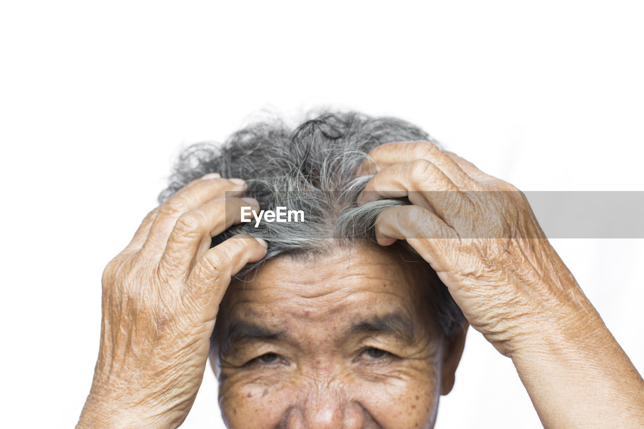 Cropped image of senior woman scratching head against white background
