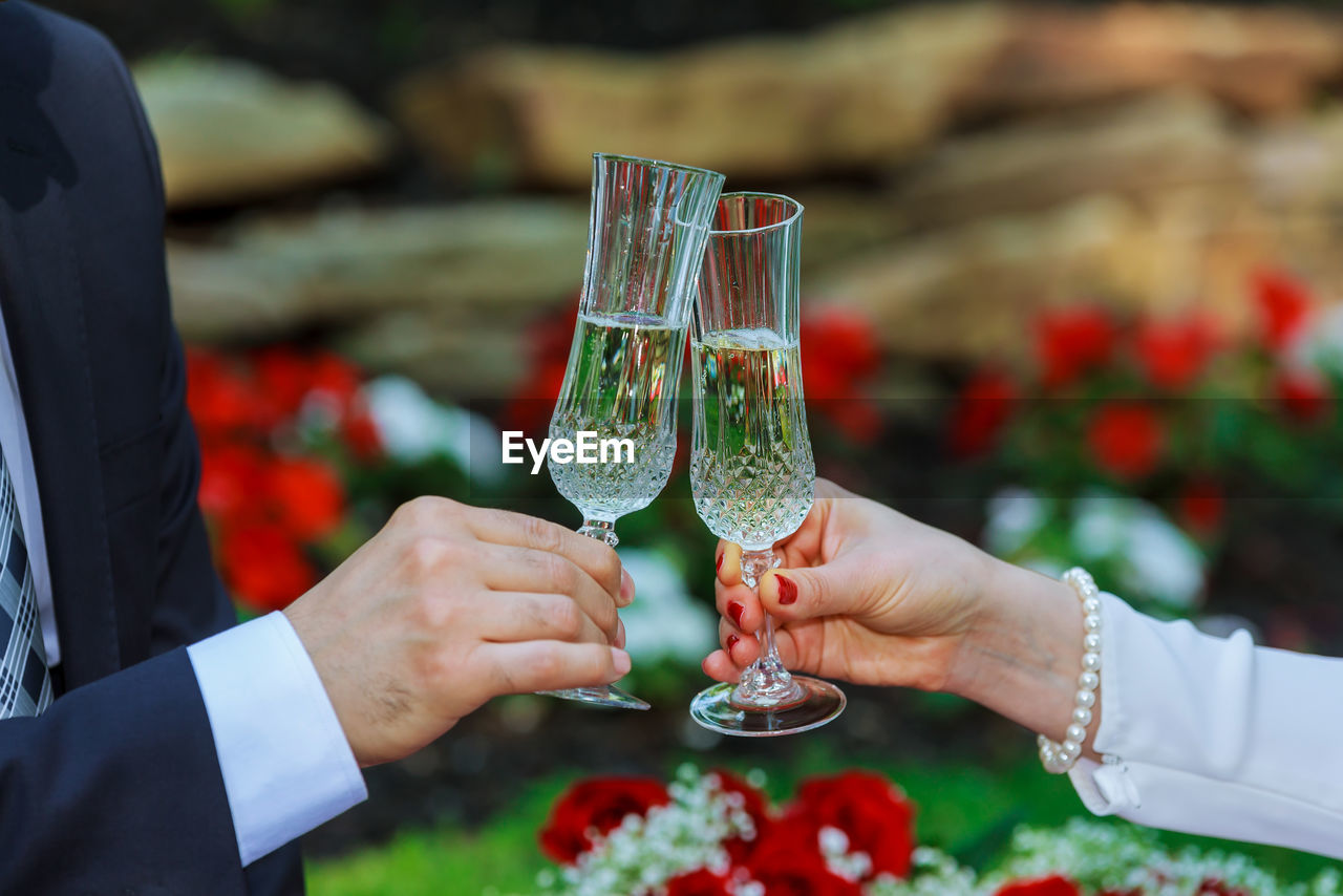 Cropped hand of groom toasting champagne flute to bride during wedding ceremony