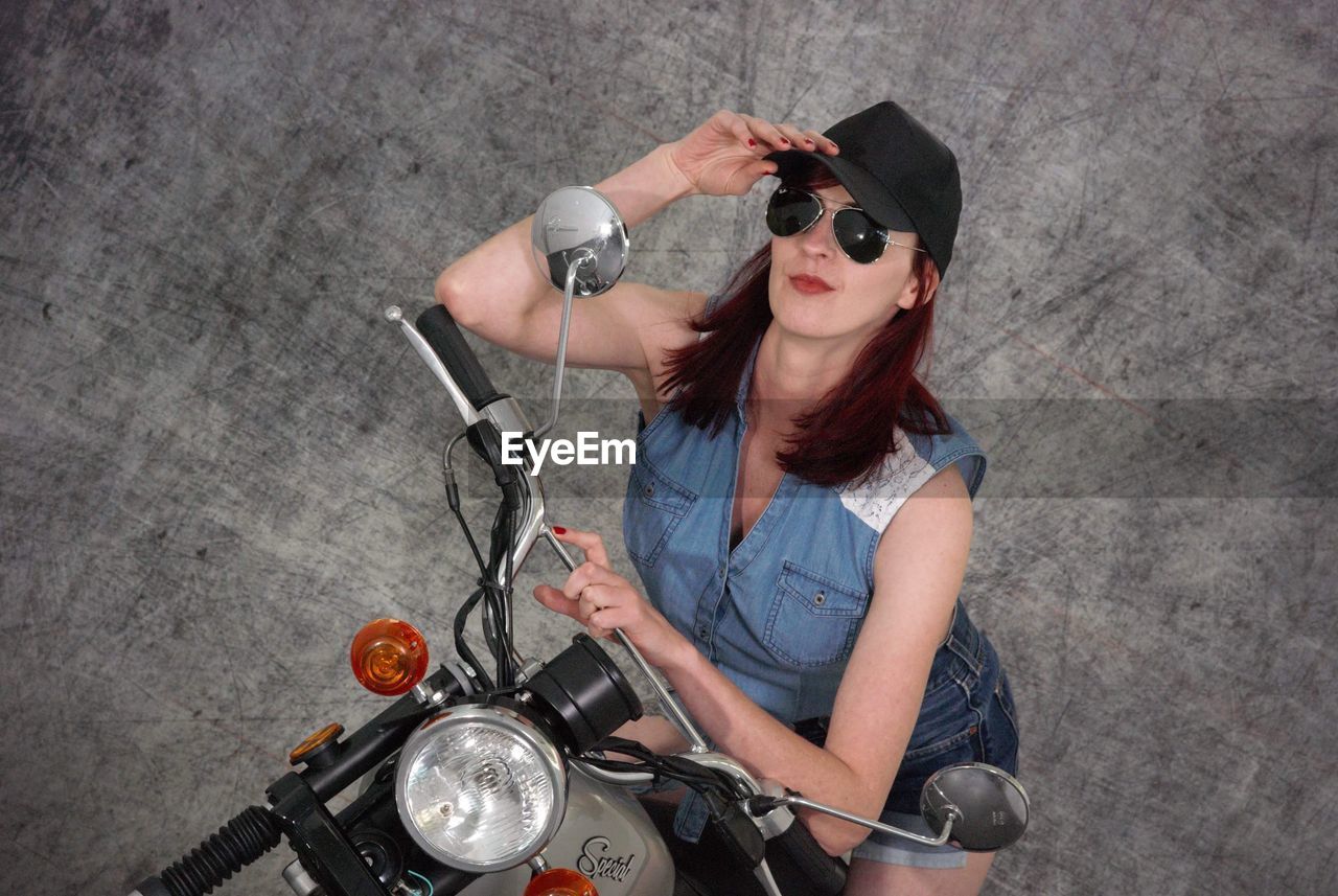 PORTRAIT OF WOMAN RIDING MOTORCYCLE WITH SUNGLASSES AND CARS