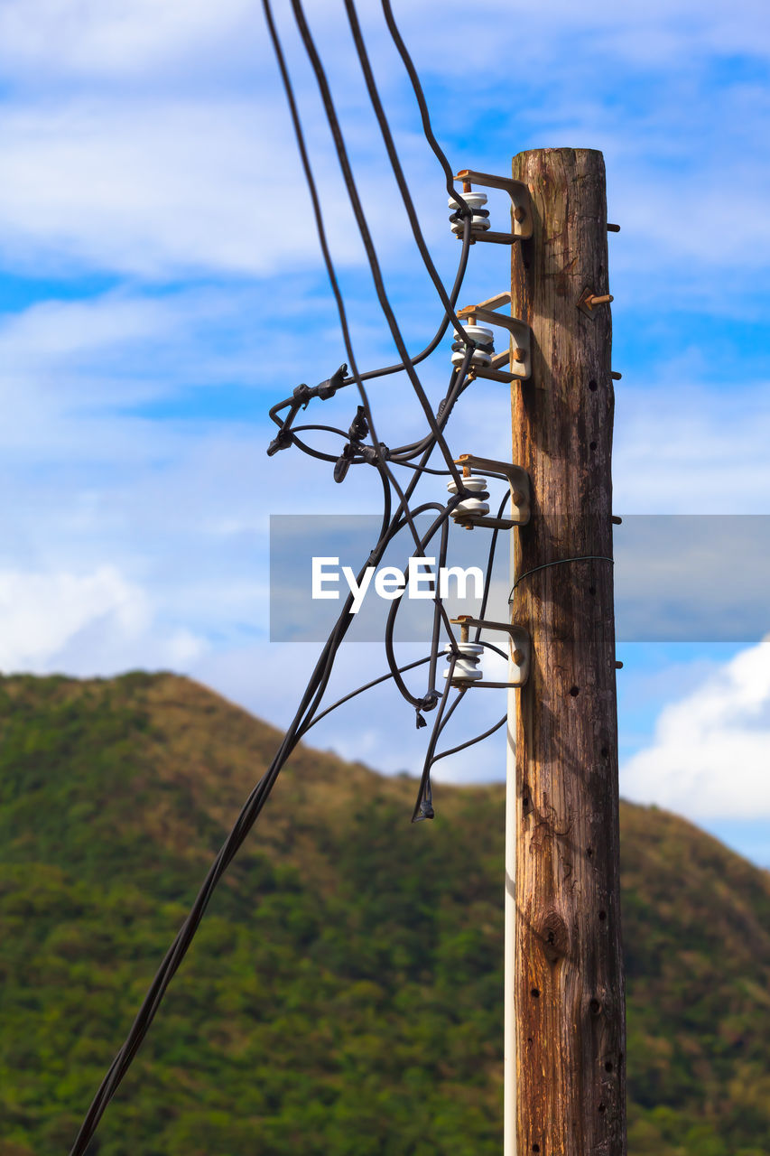 cloud, sky, cable, nature, overhead power line, no people, electricity, technology, landscape, environment, day, wind, outdoor structure, wood, tree, plant, land, mountain, mast, outdoors, scenics - nature, pole, wire, electricity pylon, power generation, tower, transmission tower, blue, wooden post, power supply, power line, beauty in nature, non-urban scene, rural scene