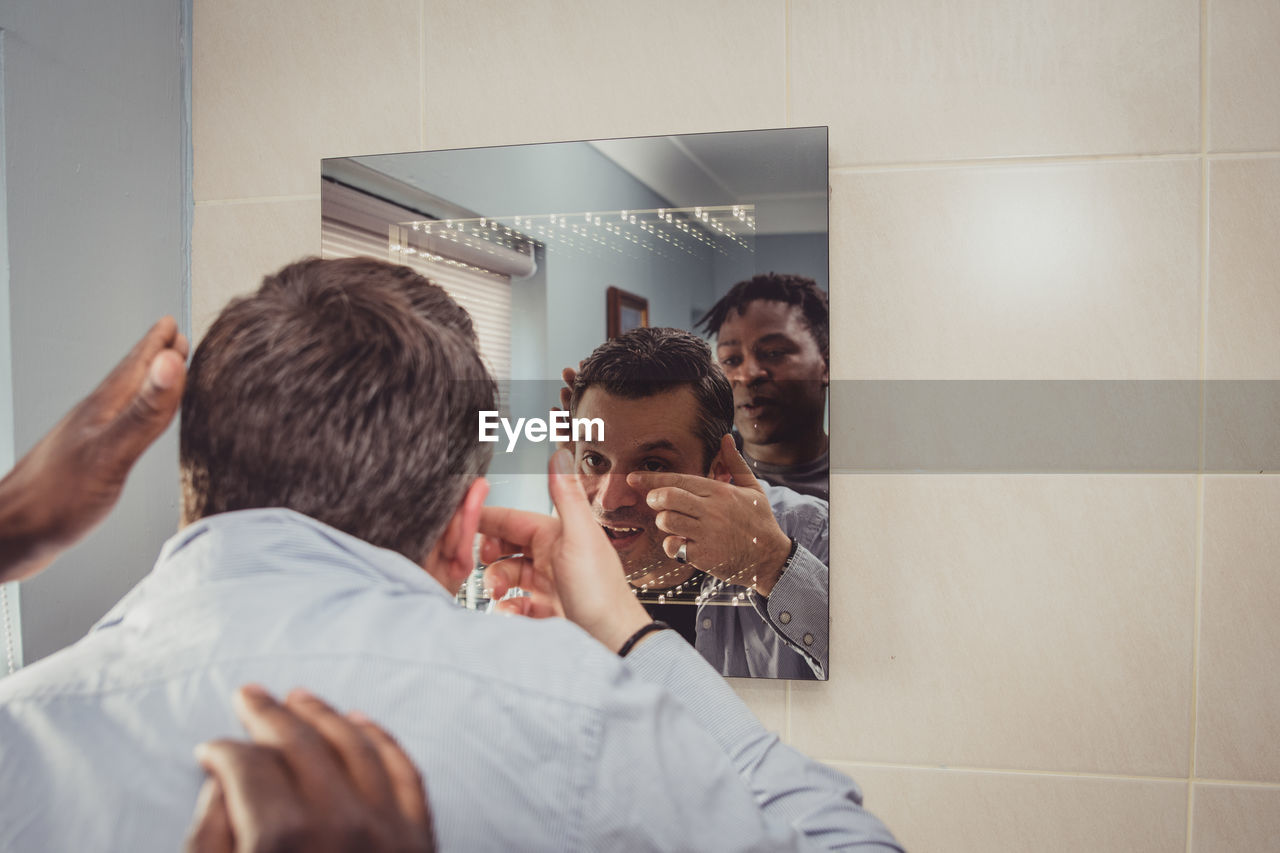 Friends talking while reflecting in mirror at home