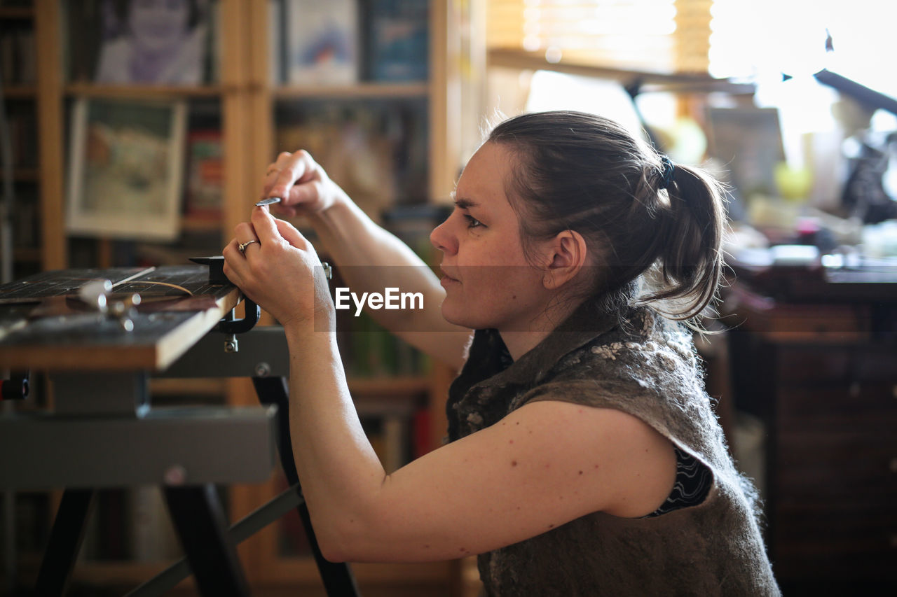 Craftsman woman works with decoration, makes the base of copper metal under the enamel, the concept 