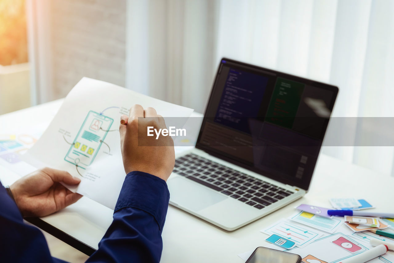 Cropped hands of software developer holding document on table