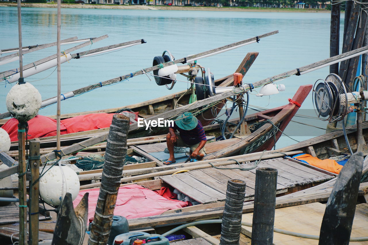 Fisherman on boat moored at lake