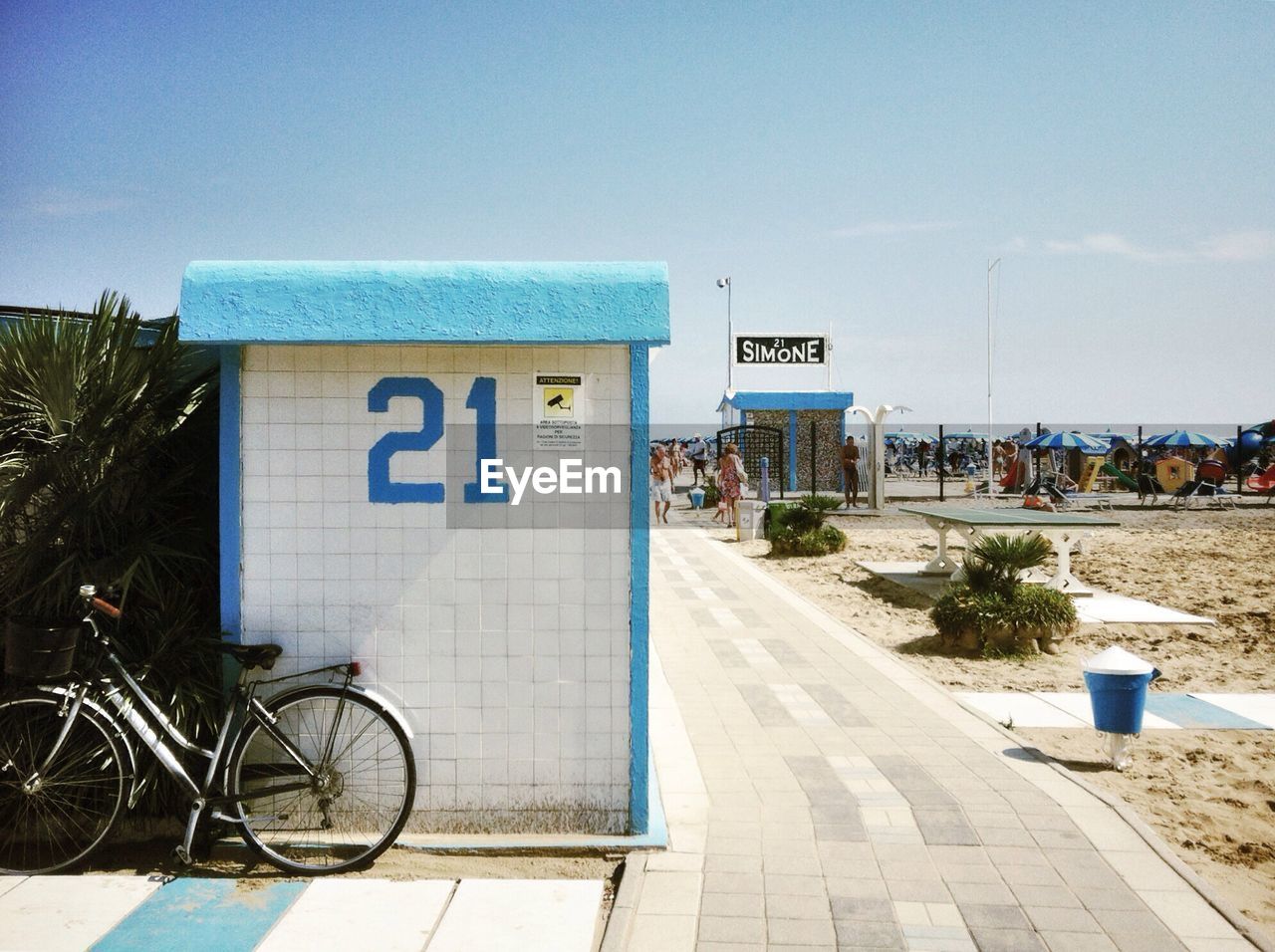 Bicycle parked against beach hut by walkway