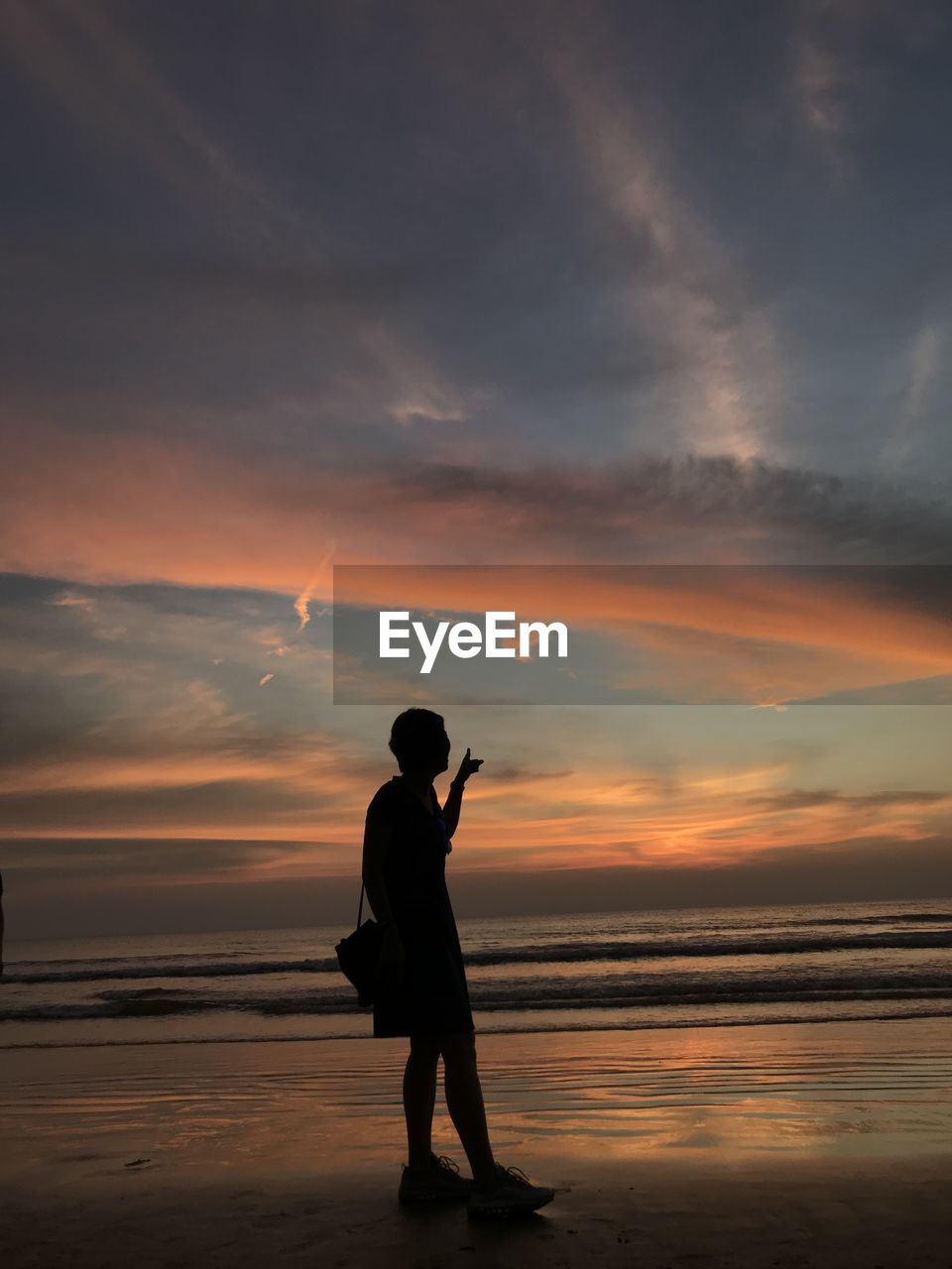 SILHOUETTE OF MAN STANDING ON BEACH AGAINST SKY DURING SUNSET