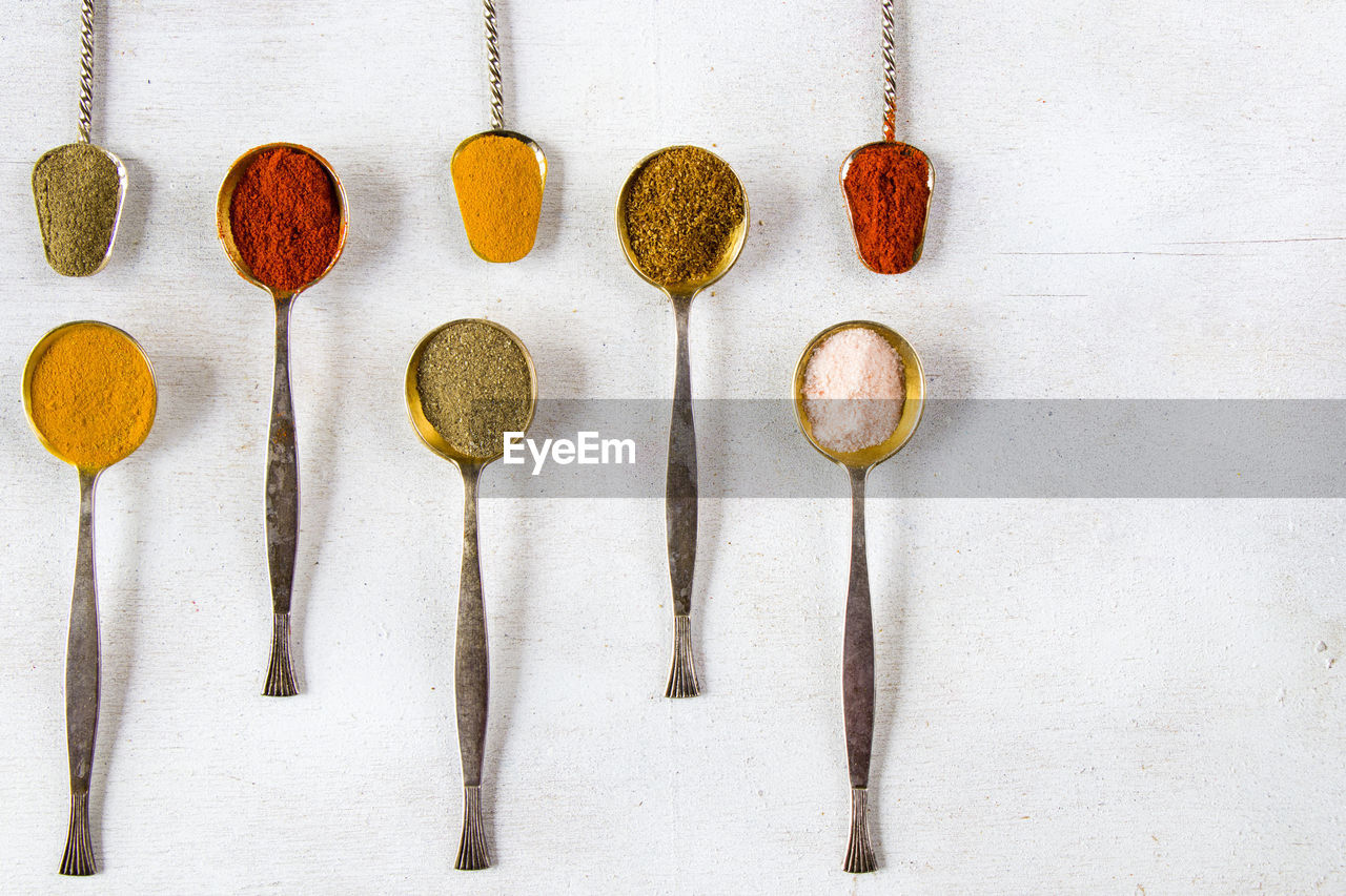 Variation of spices on the vintage silver spoons, all spices on the table, colorful food background