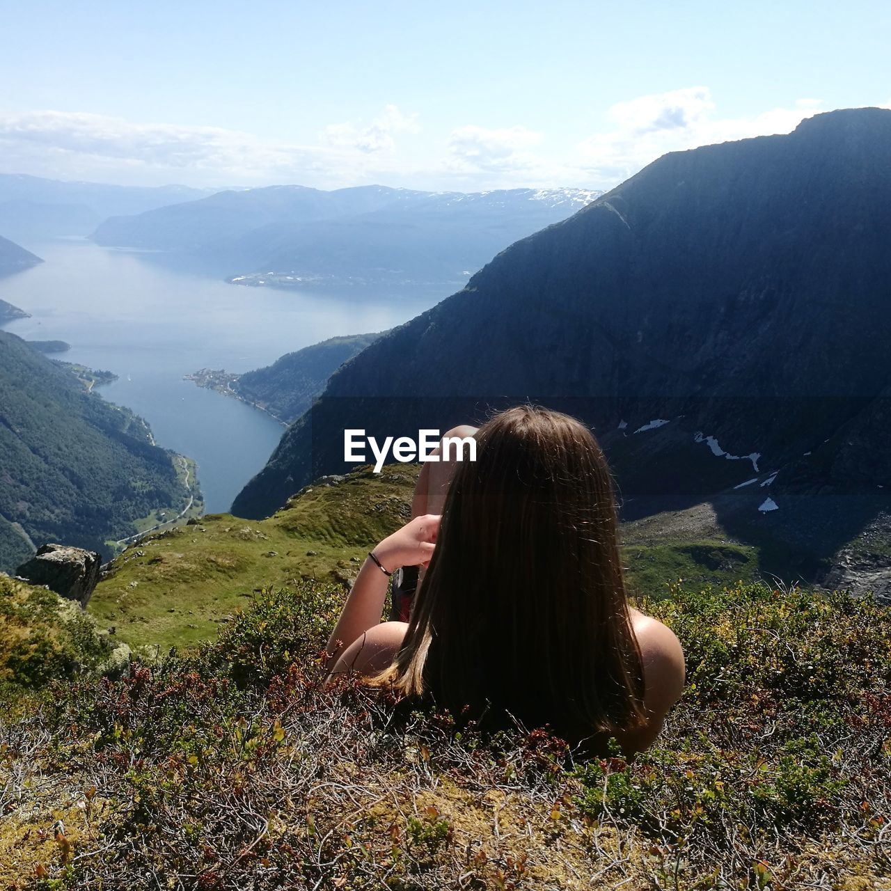 Rear view of girl lying on mountain against fjord