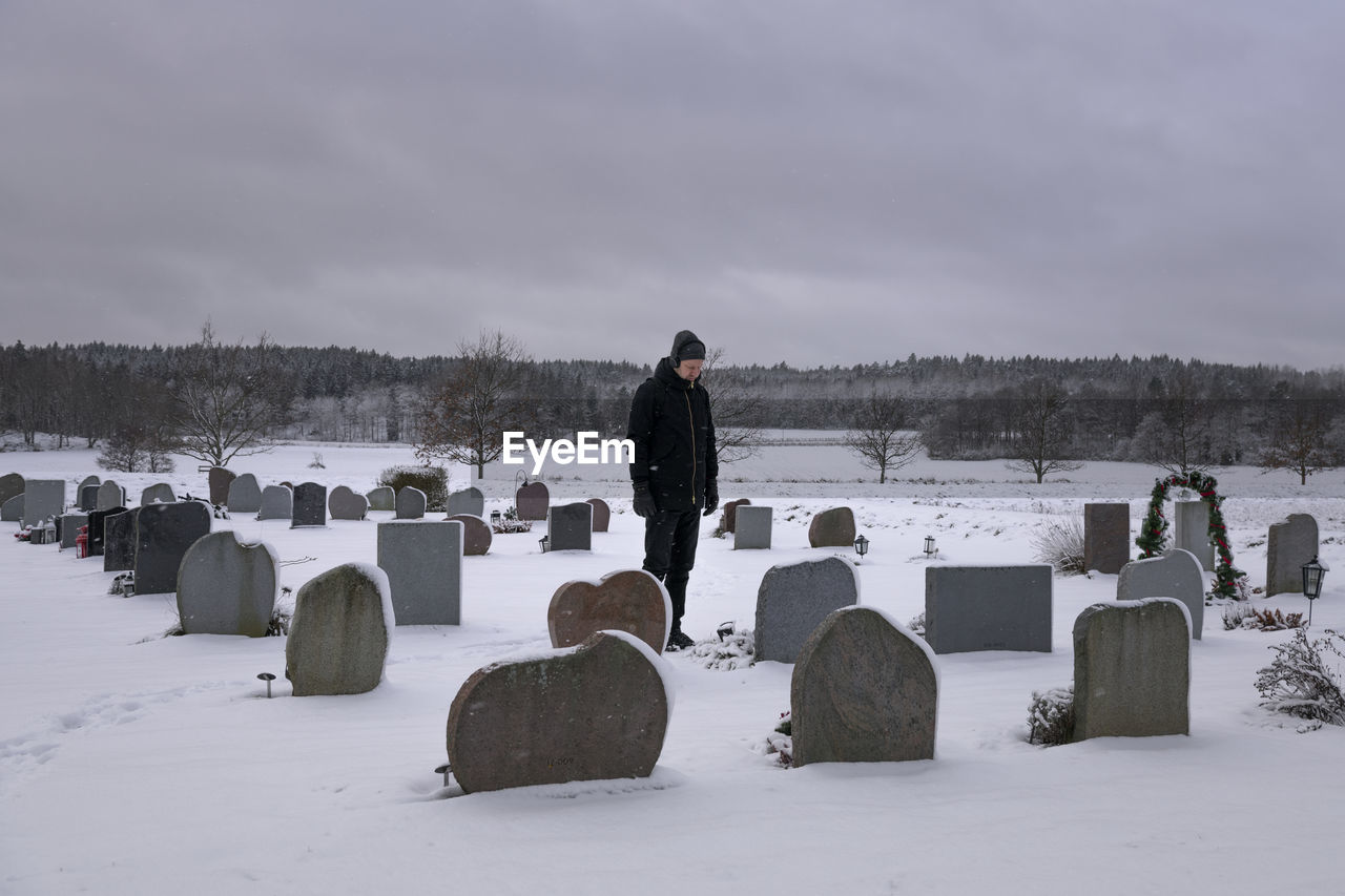 Man standing over grave at cemetery