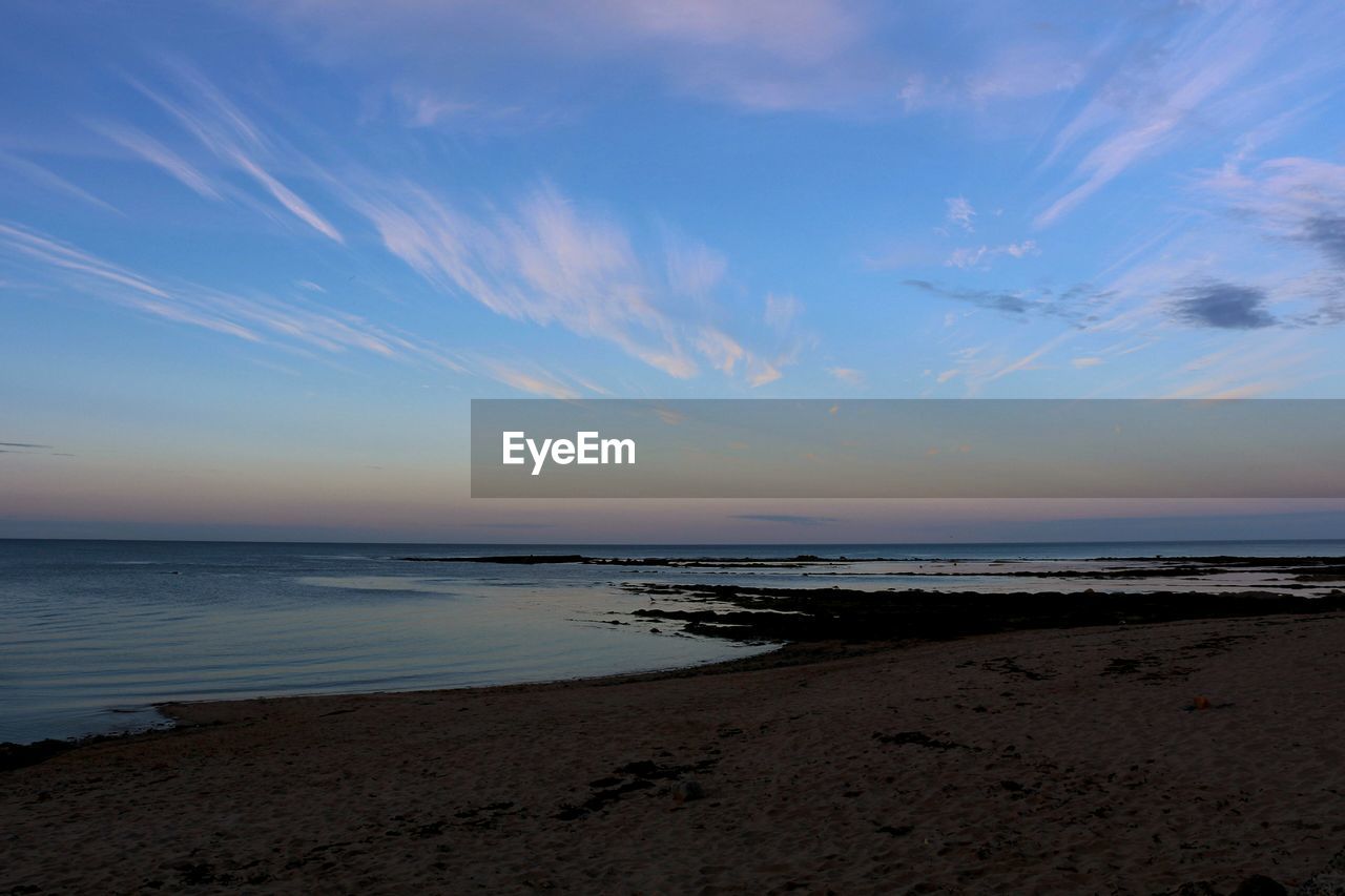 Scenic view of beach against sky at dusk