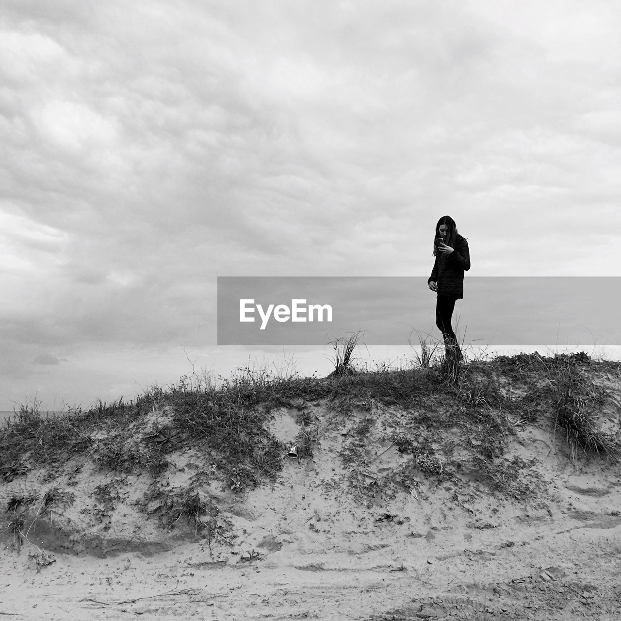 Full length of woman standing on hill against cloudy sky