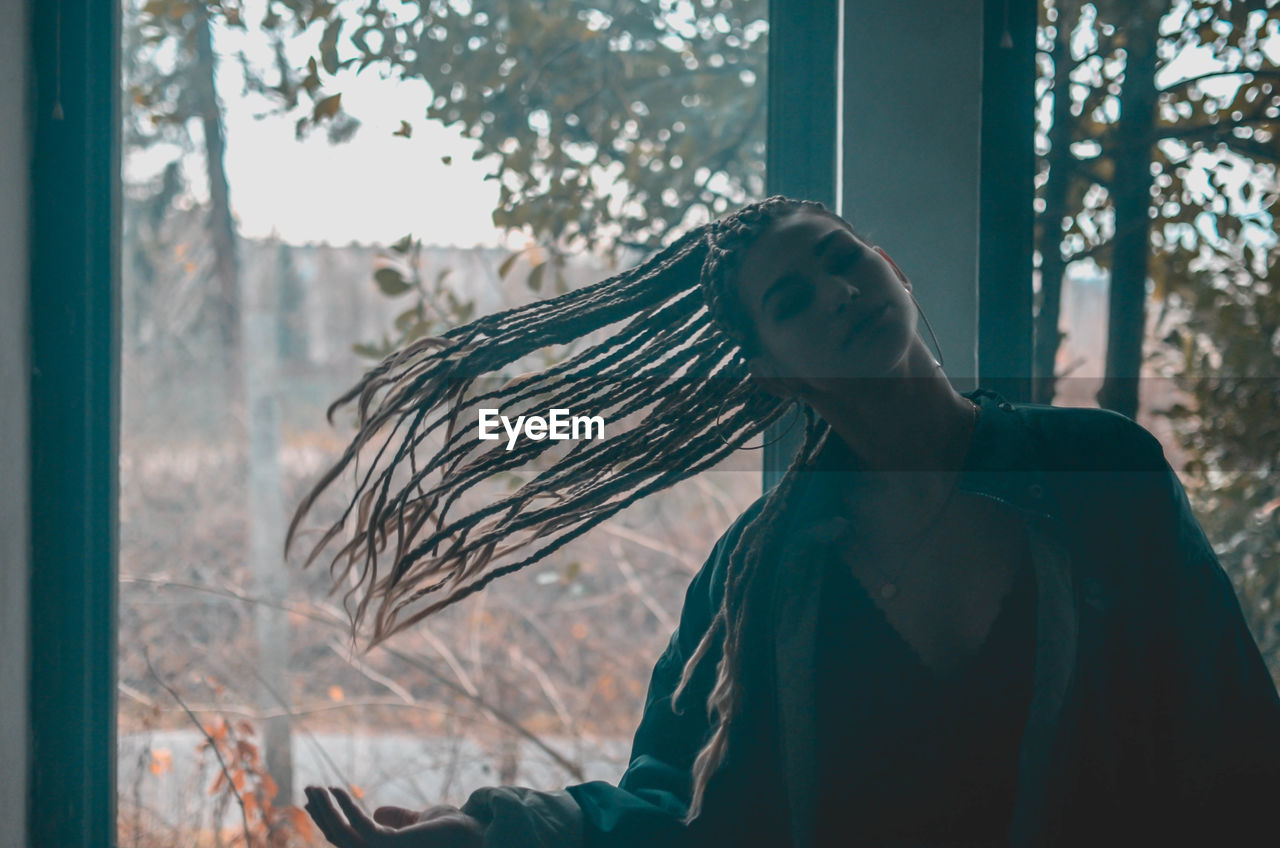 Young woman tossing hair against window