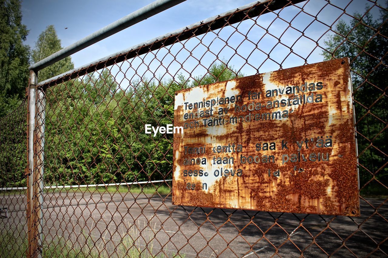 CLOSE-UP OF SIGN ON CHAINLINK FENCE