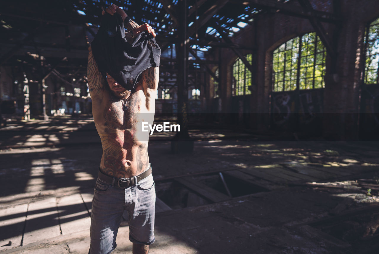 Man removing t-shirt while standing on footpath