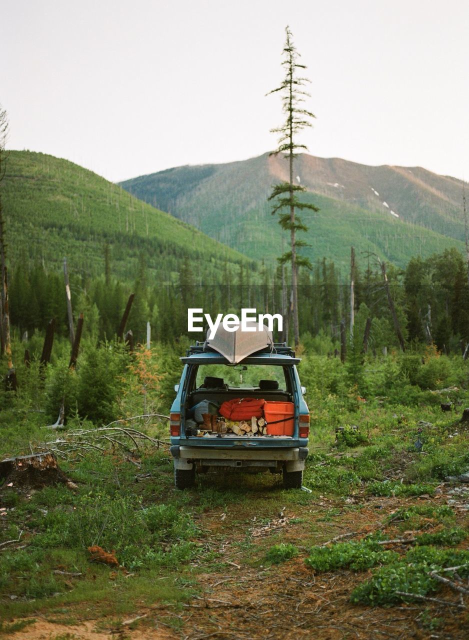 Van on field by mountain against sky