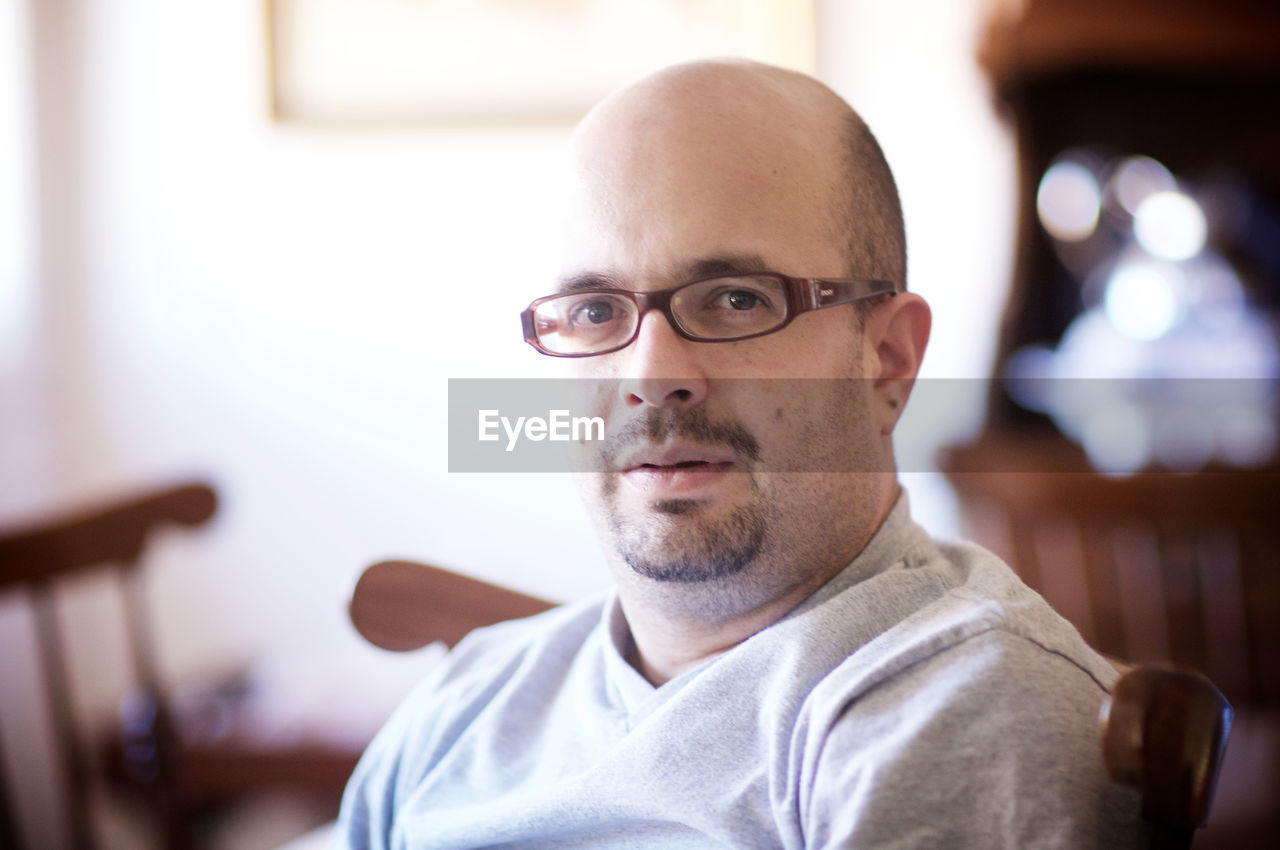 Portrait of mature man in eyeglasses sitting at home