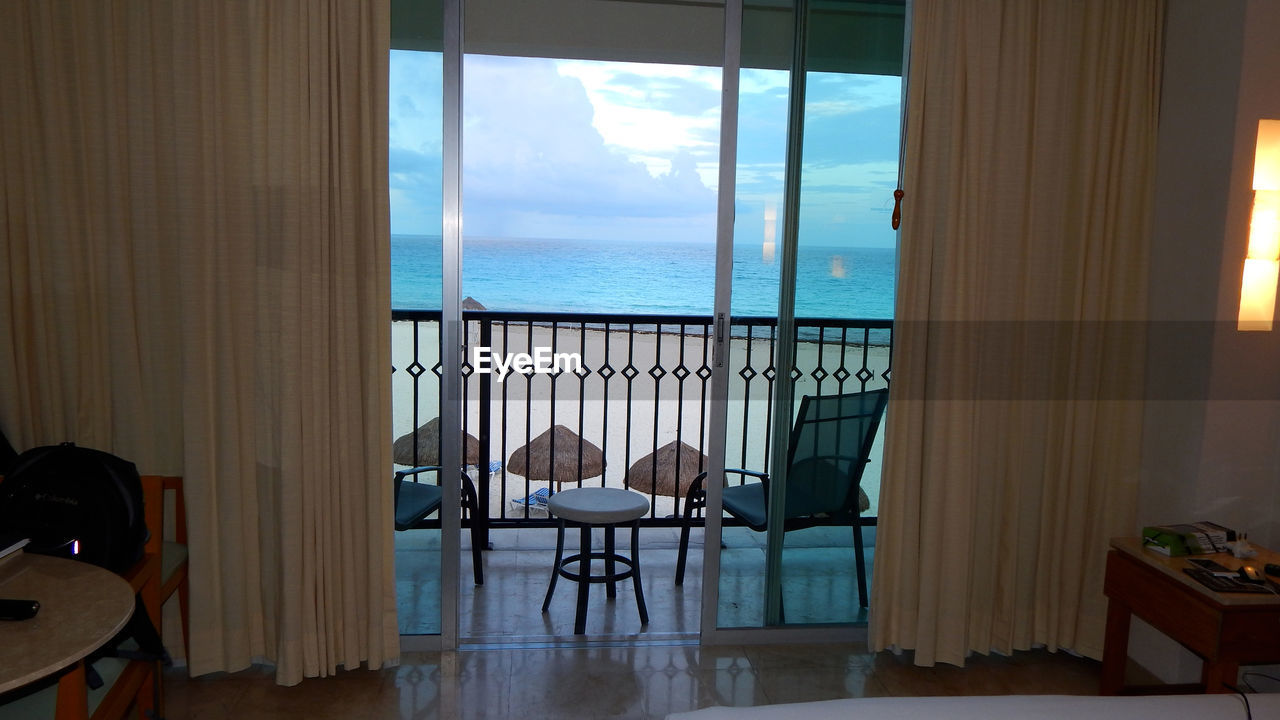 CHAIRS AND TABLE BY SEA SEEN THROUGH WINDOW