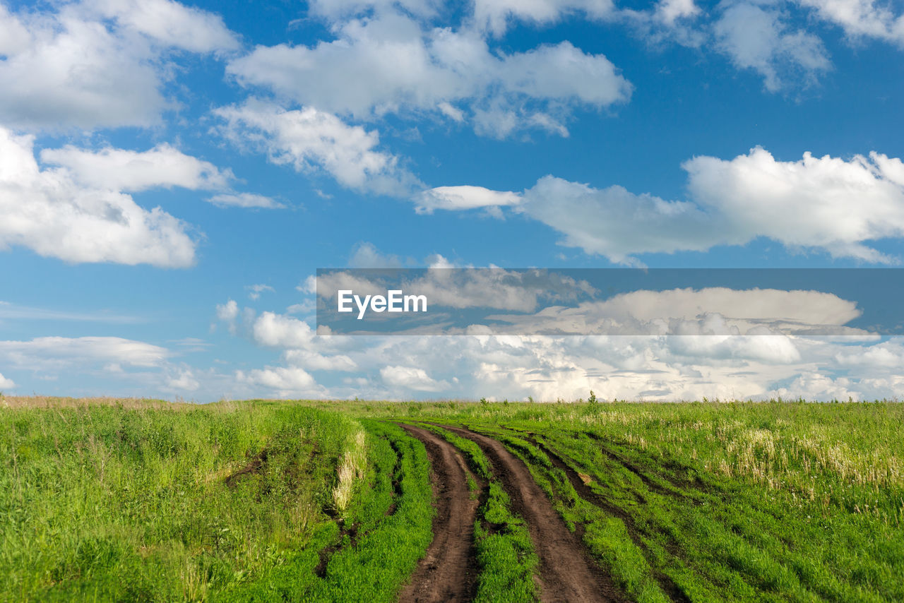 Scenic view of country road in the field against sky