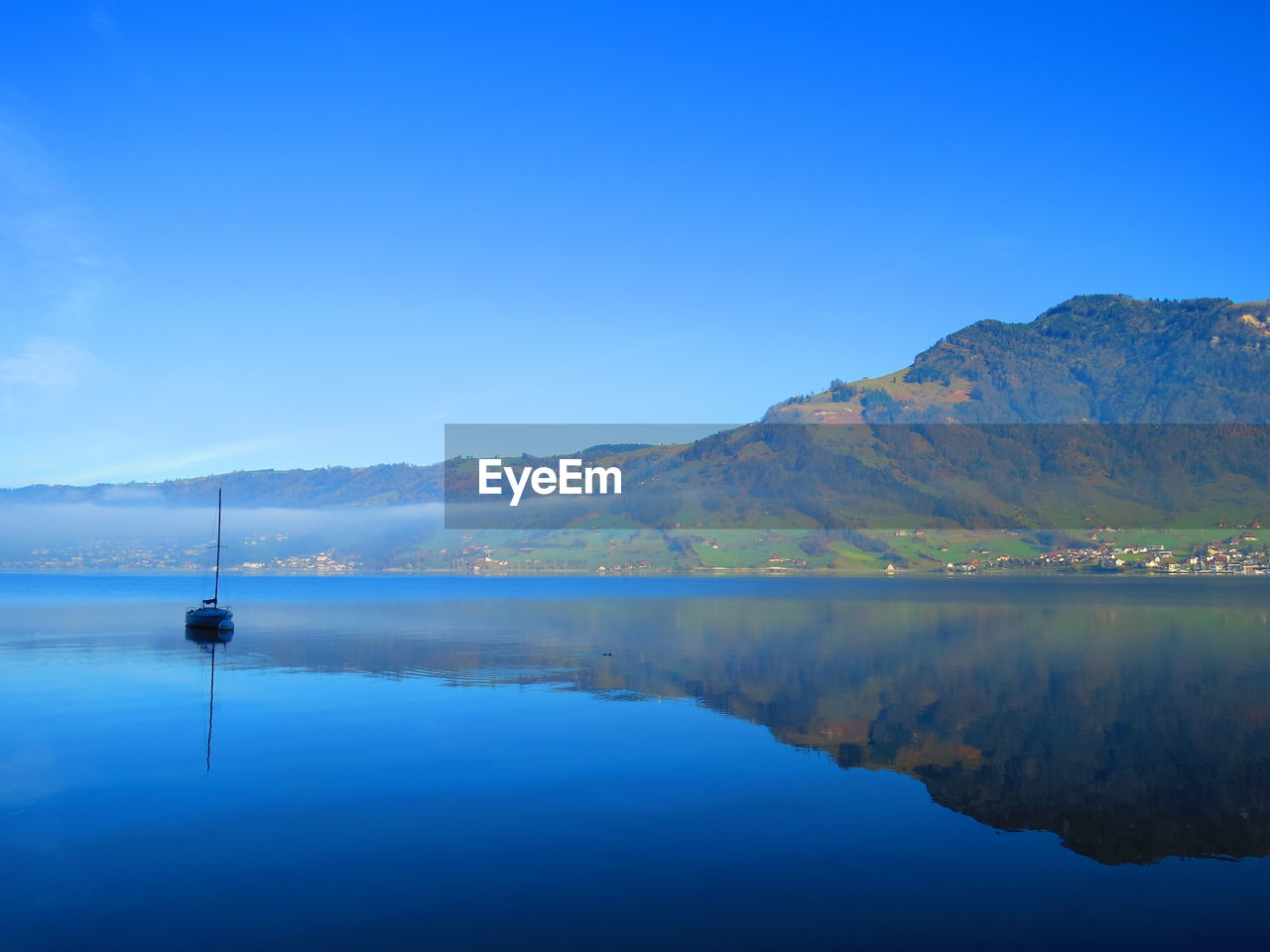 Scenic view of lake against clear blue sky