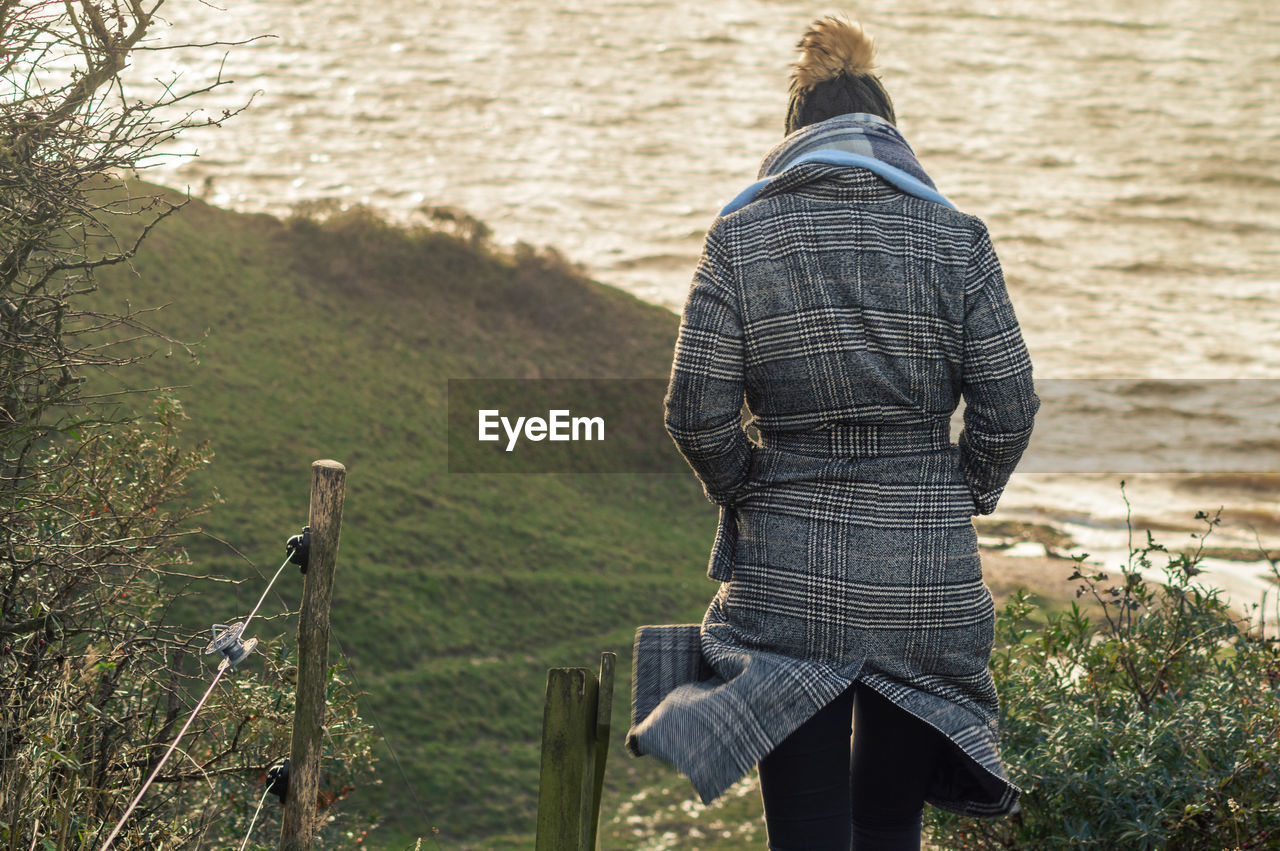 Rear view of woman standing against sea