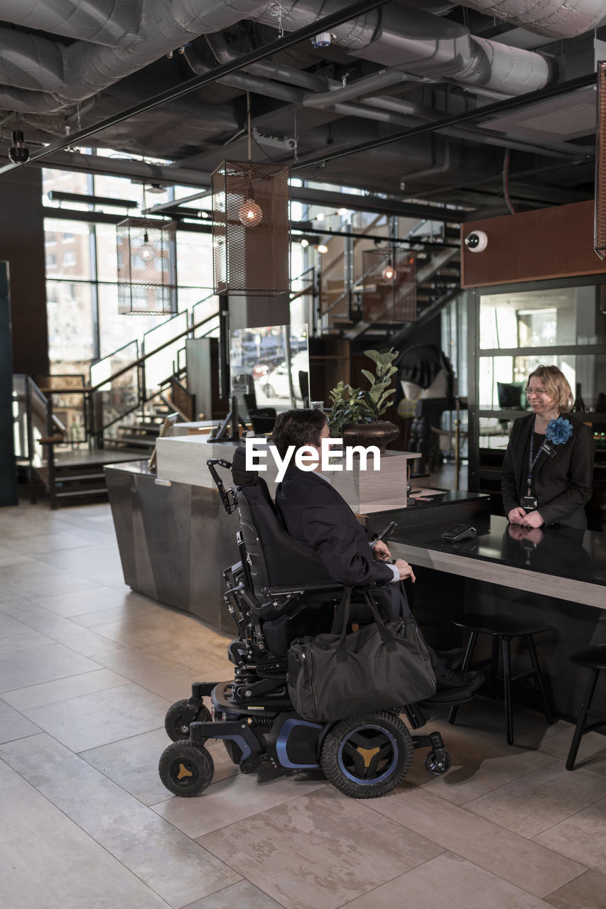Businessman on wheelchair at hotel reception desk