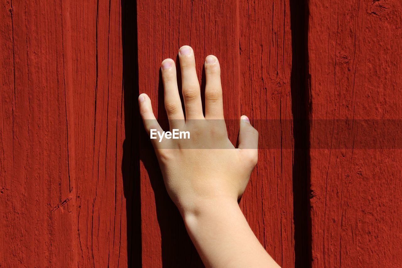 Close-up of hand on red wall