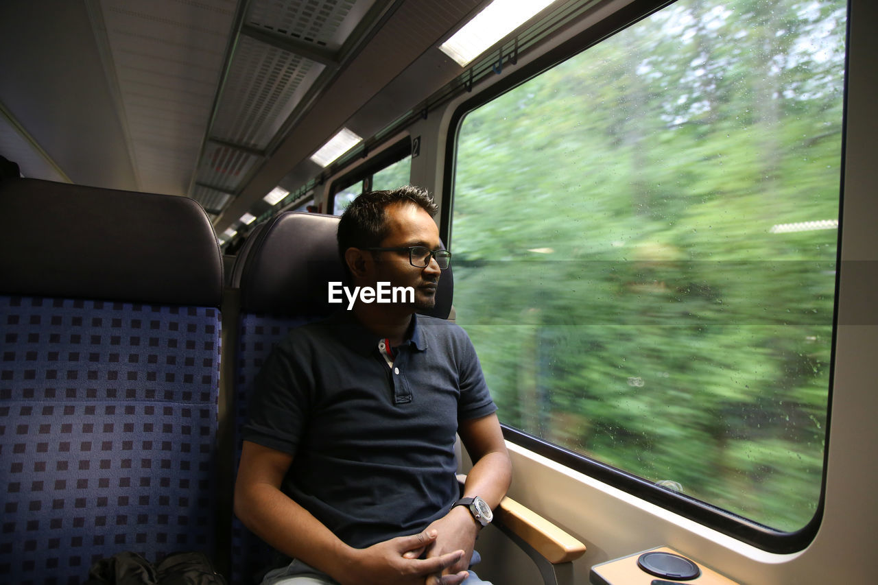 Full length of young man sitting in train in german train during day