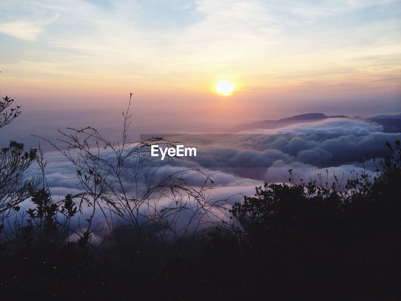 Scenic view of mountains against cloudy sky at sunset