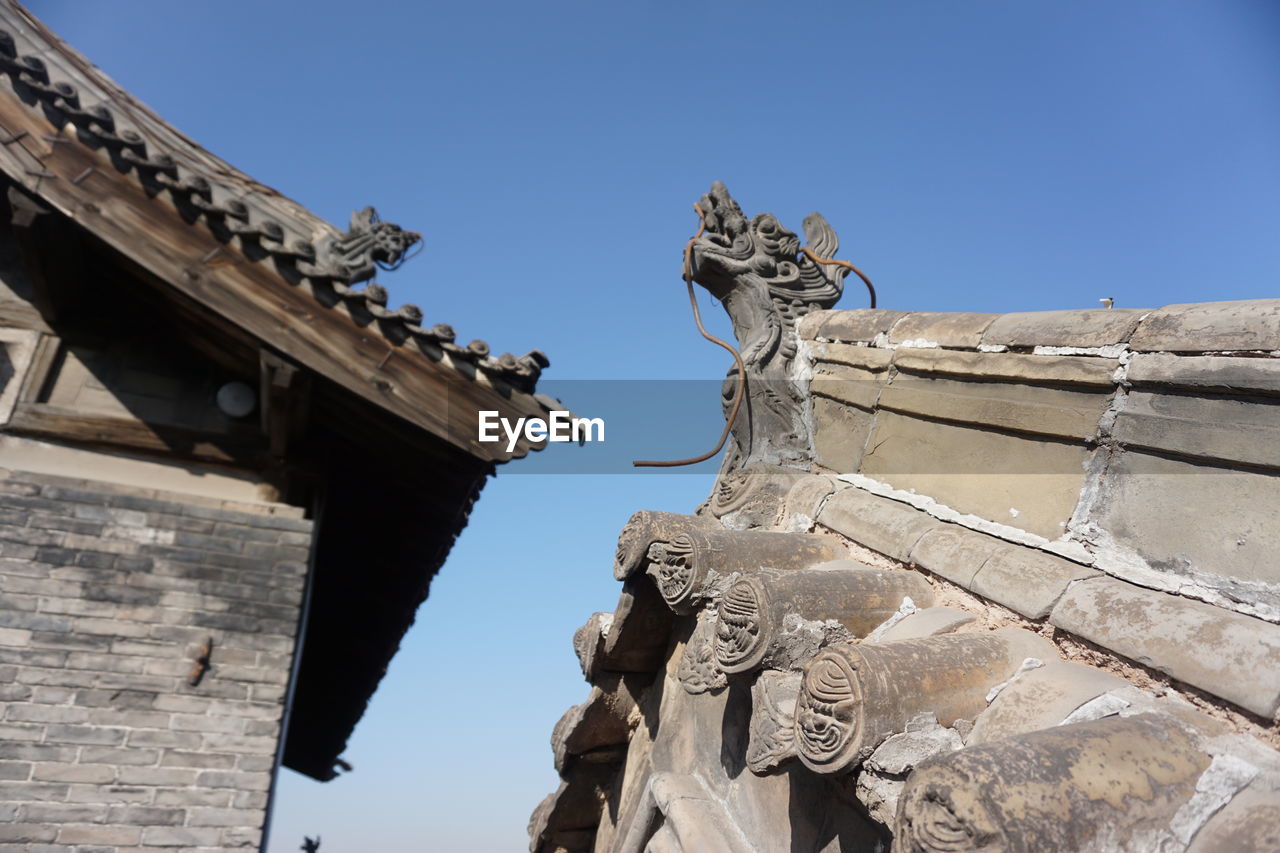 LOW ANGLE VIEW OF SCULPTURES ON BUILDING ROOF AGAINST SKY