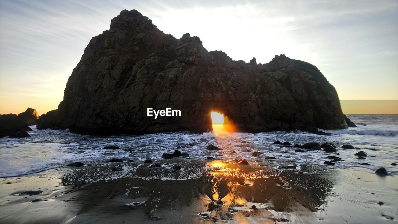 SCENIC VIEW OF ROCKS ON BEACH DURING SUNSET