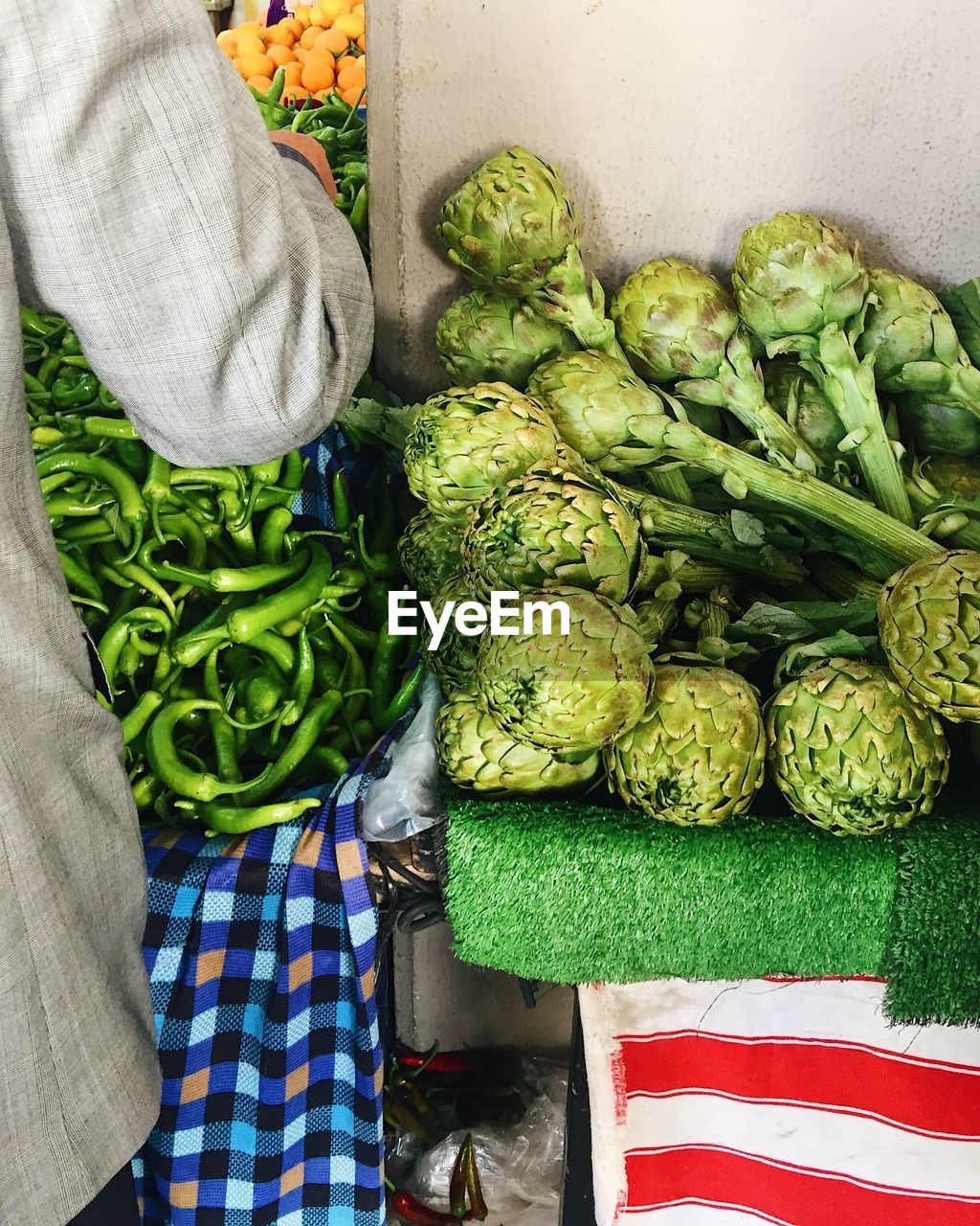 Midsection of man standing by artichokes for sale at market stall