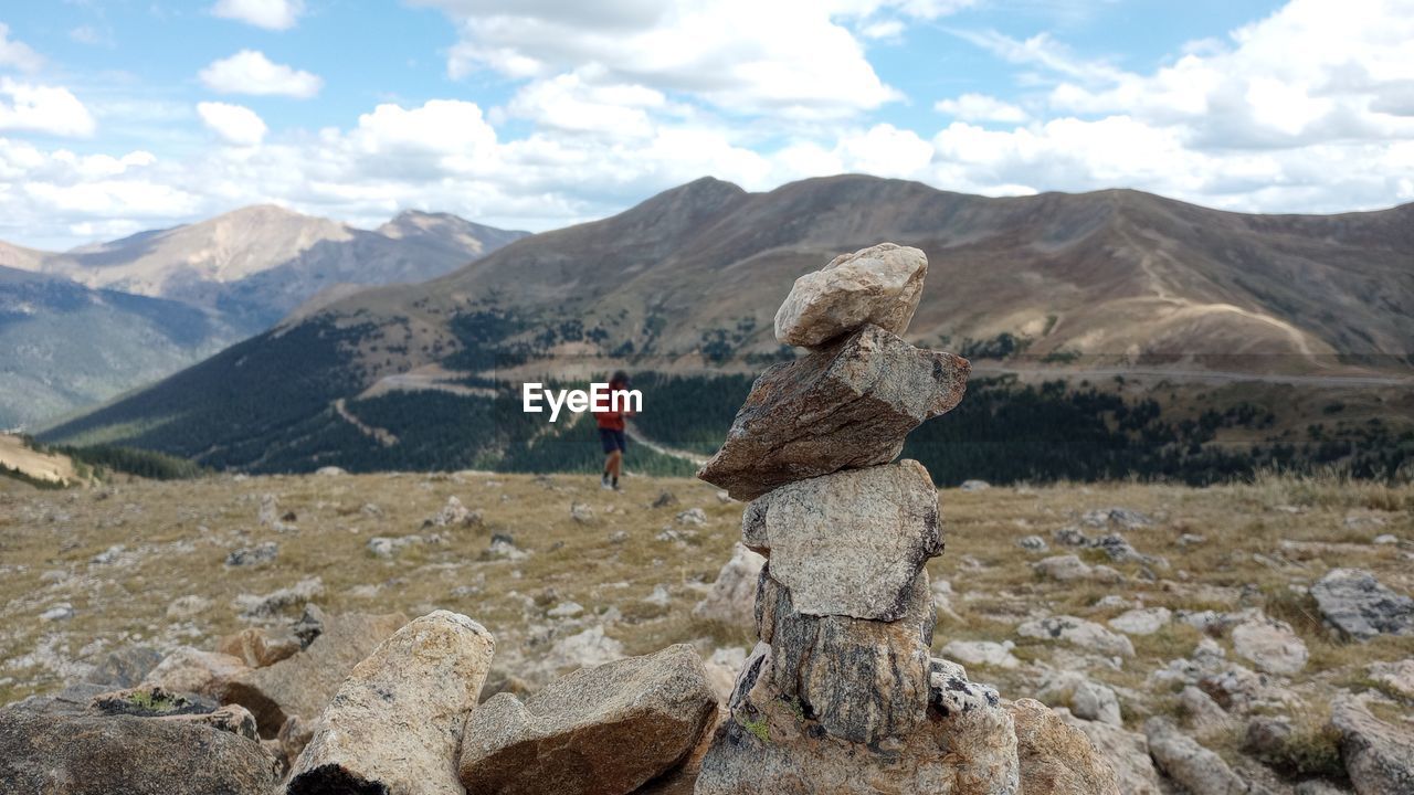 rear view of man sitting on rock against sky