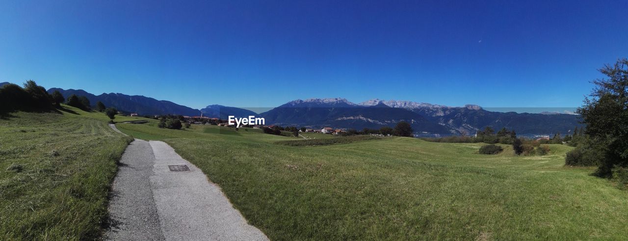 Scenic view of field and mountains against clear blue sky