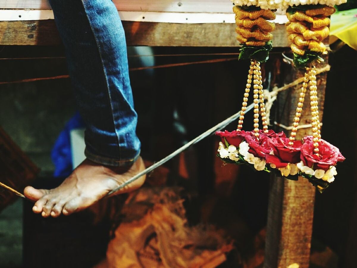 Close-up of hanging garlands and human feet on string