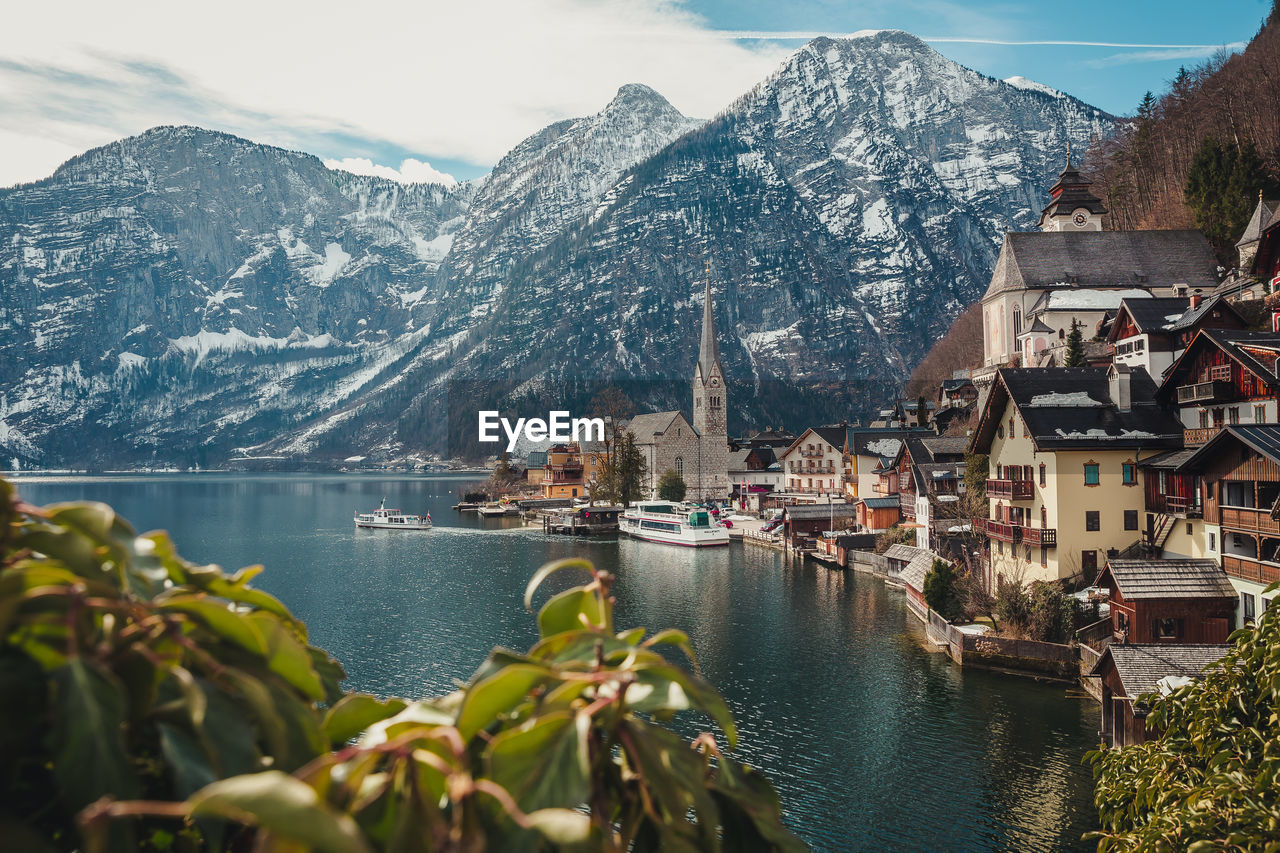 Buildings and mountains by lake against sky