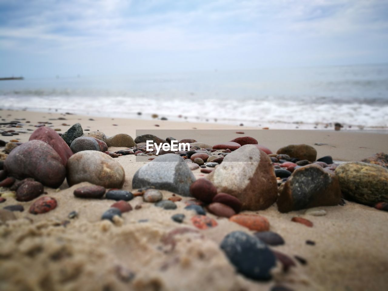 Surface level of pebbles on beach against sky