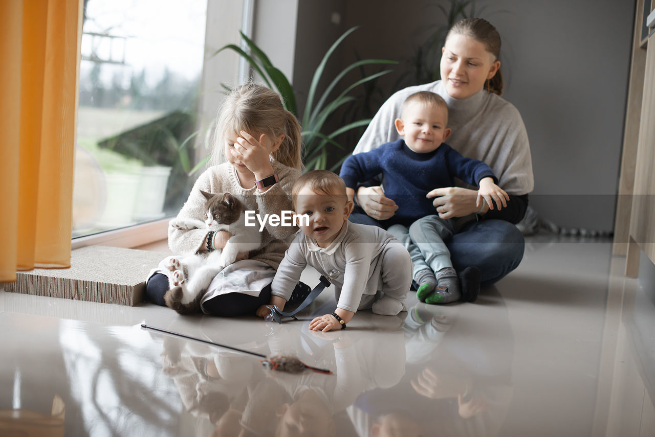 A mother with her  children playing on the floor at home during quarantine corona virus covid-19