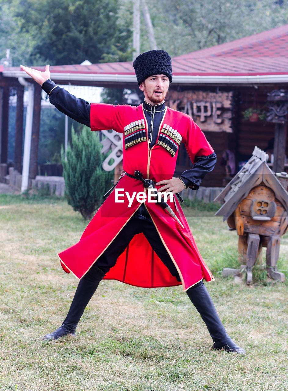 FULL LENGTH OF WOMAN WITH RED UMBRELLA STANDING ON FIELD