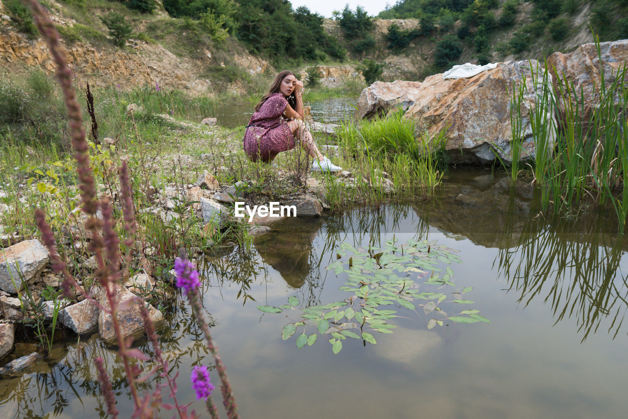 View of beautiful girl siting  by the lake